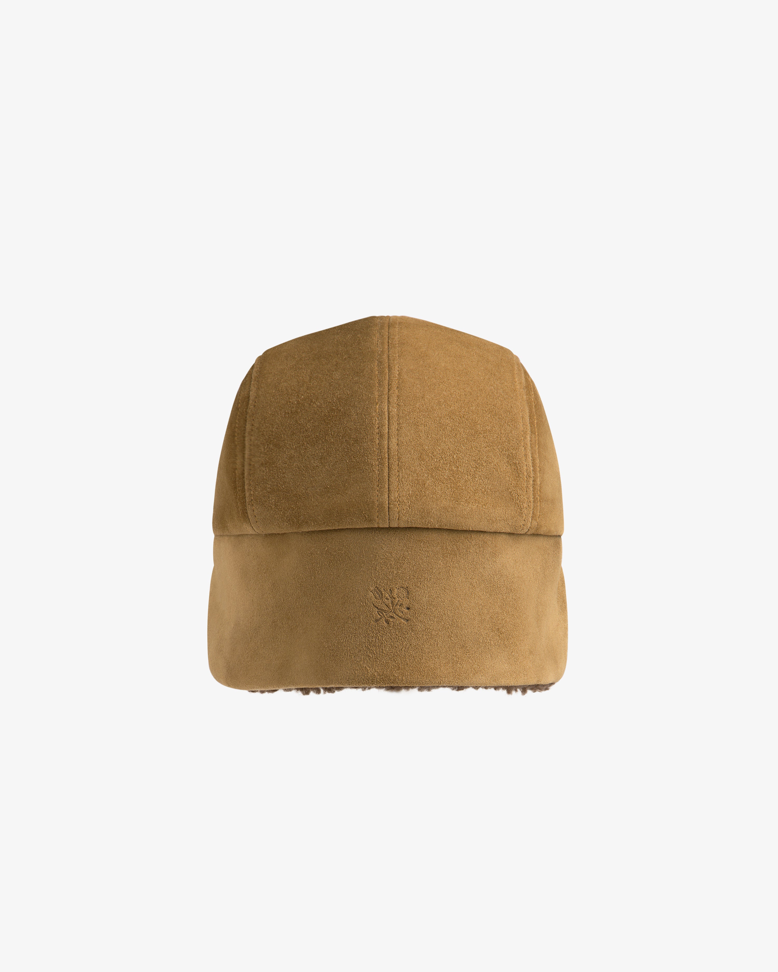 Tan suede Shearling Earflap Hat with fold-down earflaps and a small logo on the back.