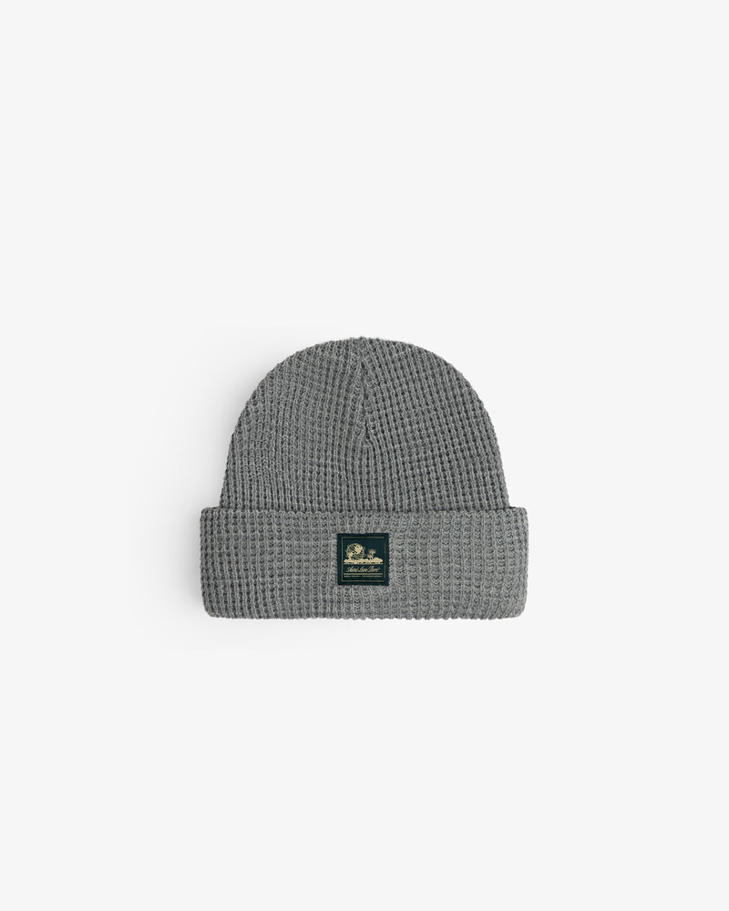 Waffle Knit Beanie in gray with folded brim and black front patch, displayed on a white background.