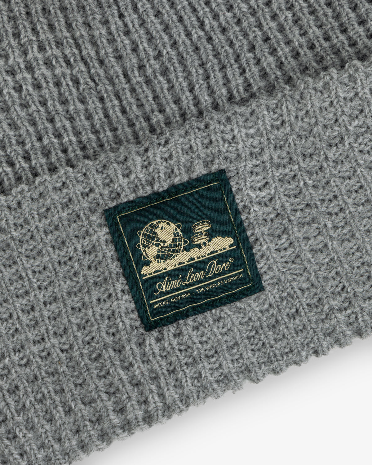 Grey Waffle Knit Beanie with a globe, books, and “Aimé Leon Dore” in gold on a woven patch.