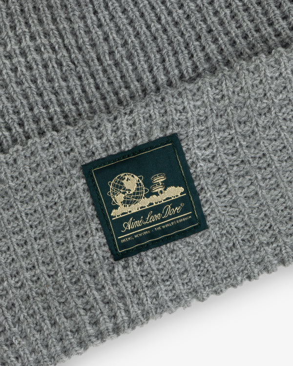 Grey Waffle Knit Beanie with a globe, books, and “Aimé Leon Dore” in gold on a woven patch.
