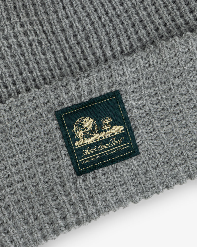 Grey Waffle Knit Beanie with a globe, books, and “Aimé Leon Dore” in gold on a woven patch.
