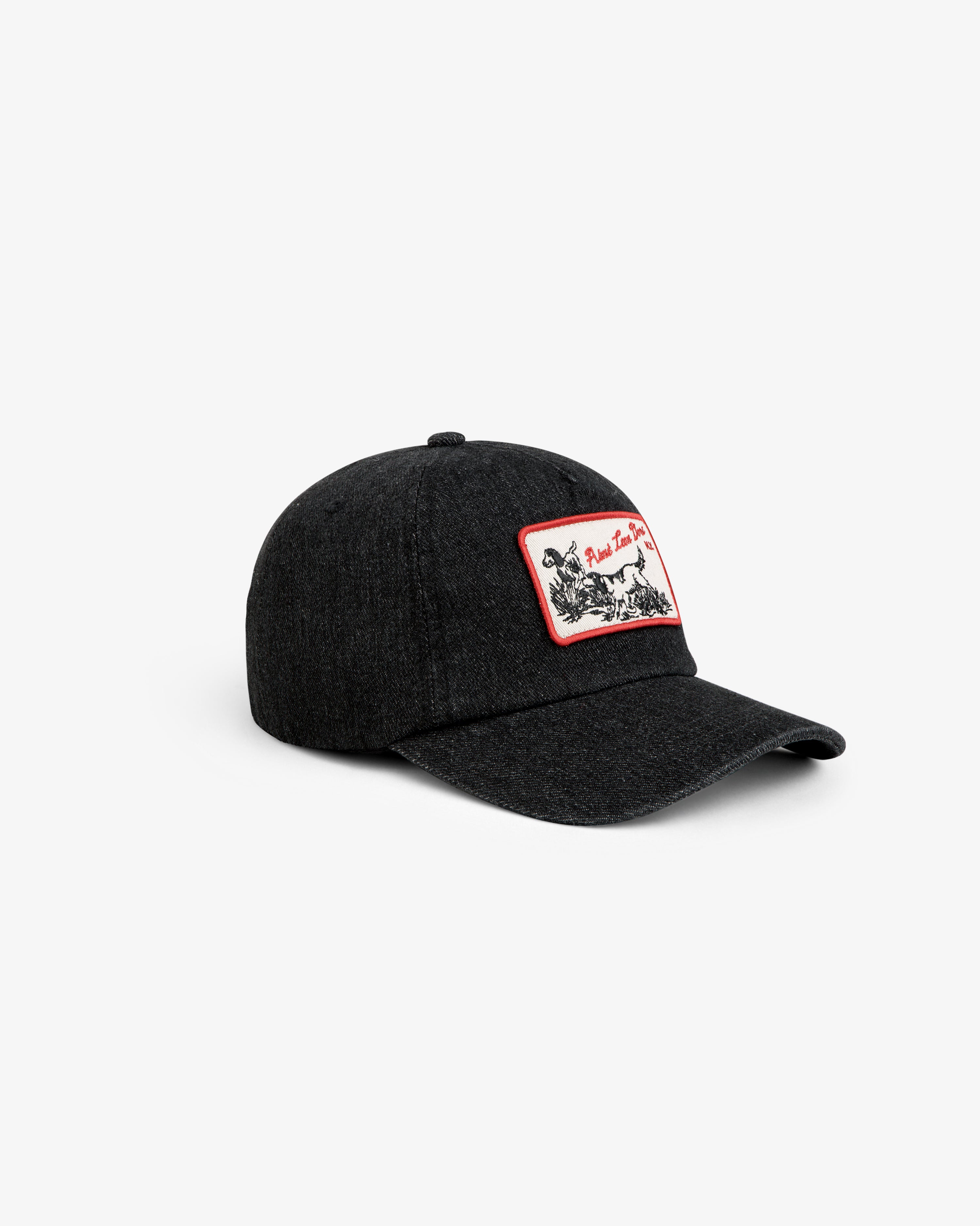 Aimé Retriever Hat: a black baseball cap with a rectangular patch featuring a red border and a black-and-white dog graphic.