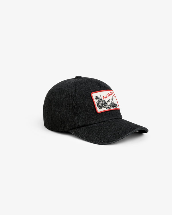 Aimé Retriever Hat: a black baseball cap with a rectangular patch featuring a red border and a black-and-white dog graphic.
