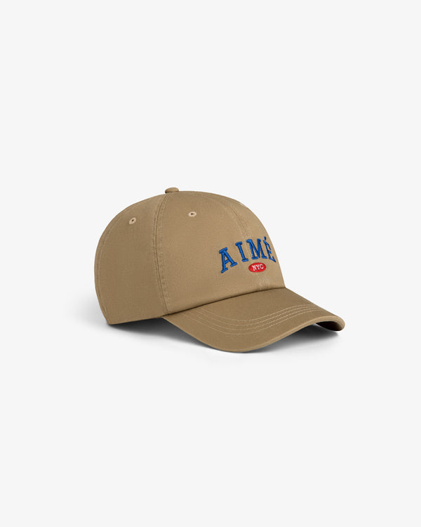 Aimé Souvenir Hat: Tan cap with blue AIMÉ embroidery and red NYC patch, displayed on a white background.