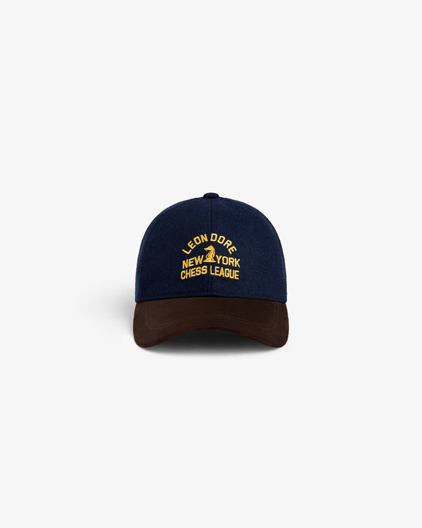 Navy blue Triborough Chess Club Wool Hat with yellow text, brown brim, on a white background.