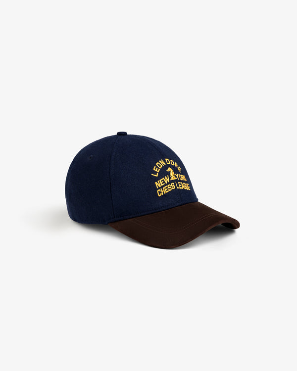 Triborough Chess Club Wool Hat: navy blue with brown brim, yellow “Leon Dore New York Chess League” embroidery.