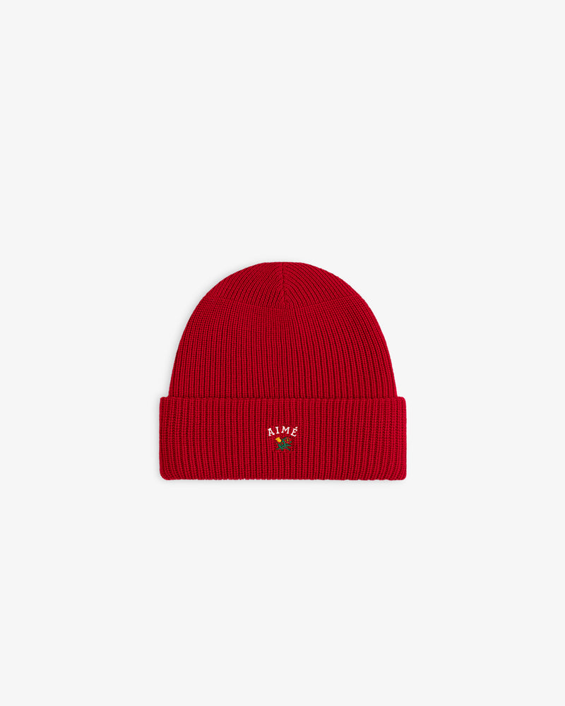 Crest Merino Wool Beanie in red with folded brim, embroidered text, and a rose at the front center.