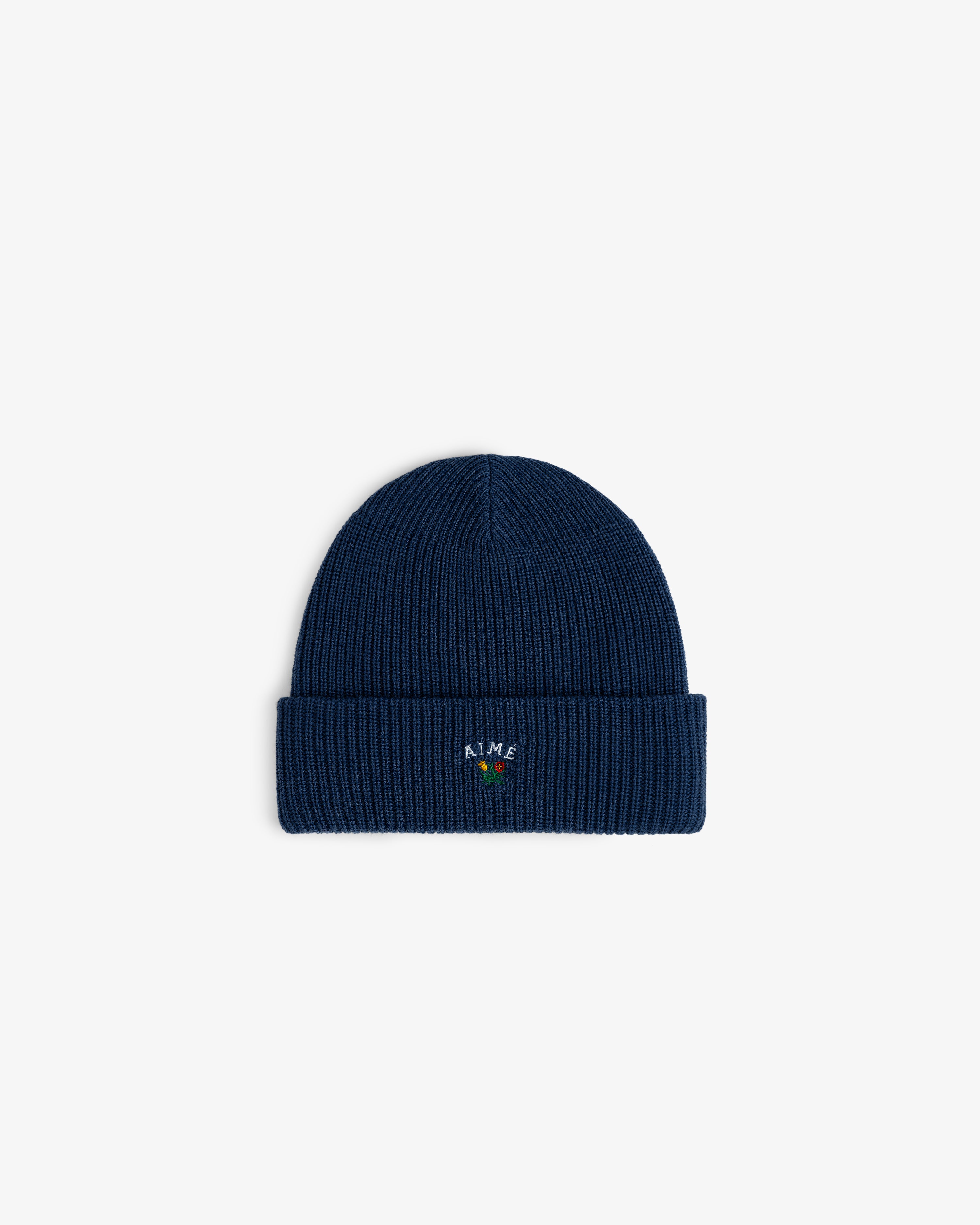 The Crest Merino Wool Beanie is navy, ribbed, with a cuff and vibrant embroidery on the front.
