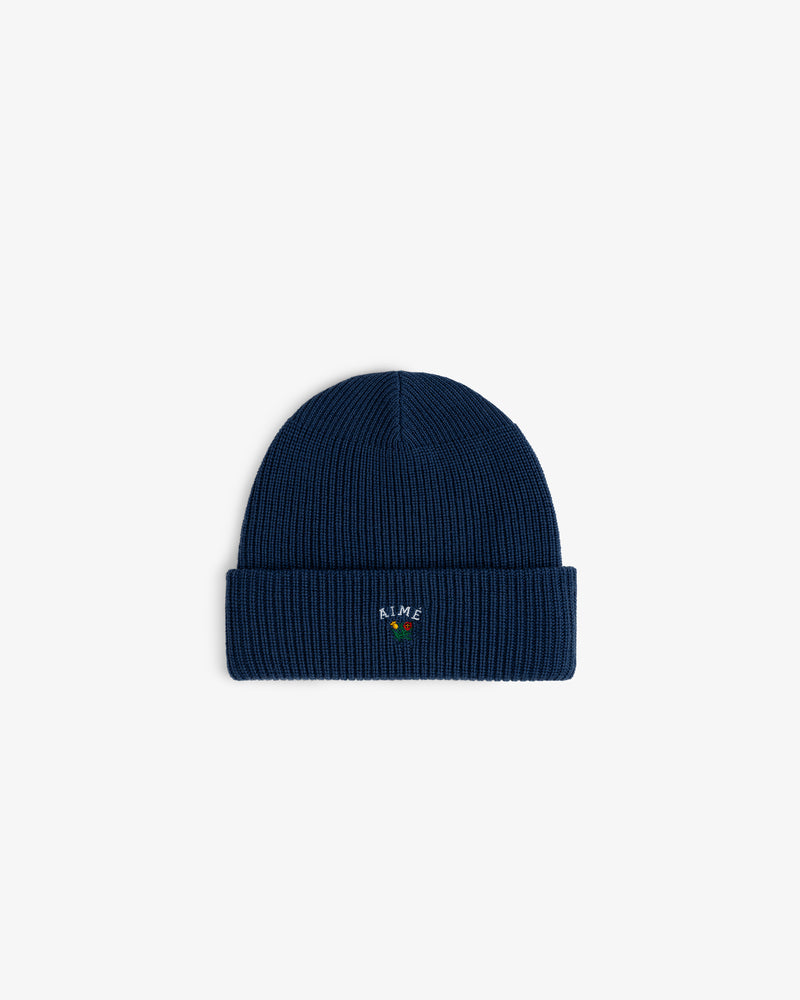 The Crest Merino Wool Beanie is navy, ribbed, with a cuff and vibrant embroidery on the front.