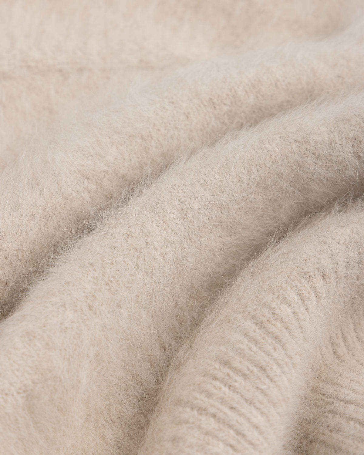 Close-up of a beige, fuzzy Fox Fur Hood with soft knit fabric folds.