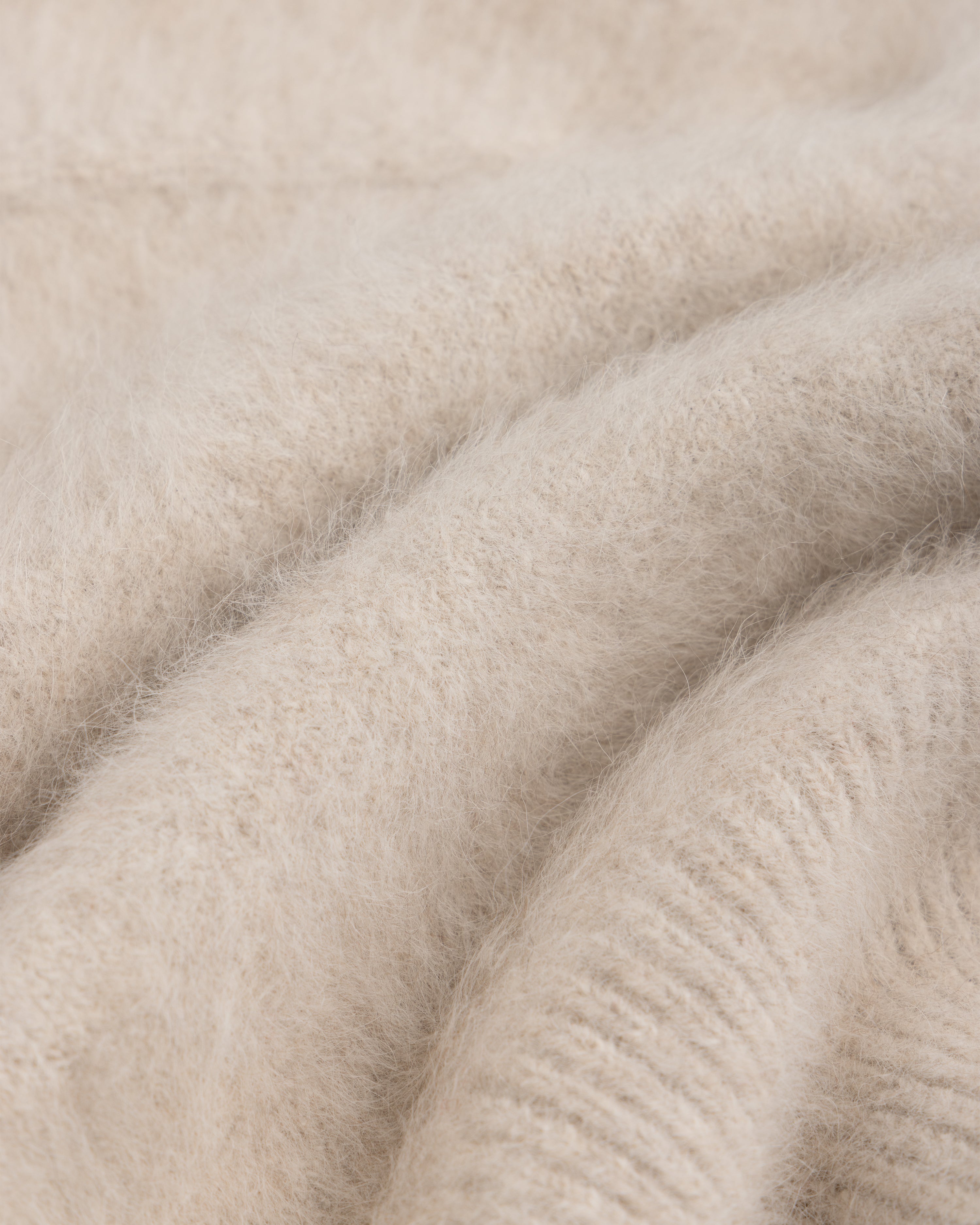 Close-up of a beige, fuzzy Fox Fur Hood with soft knit fabric folds.