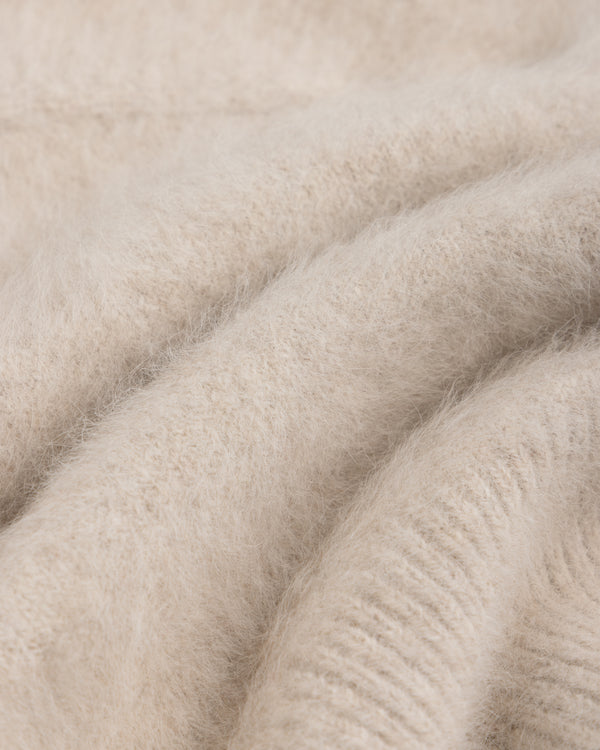 Close-up of a beige, fuzzy Fox Fur Hood with soft knit fabric folds.