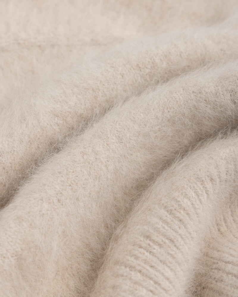 Close-up of a beige, fuzzy Fox Fur Hood with soft knit fabric folds.