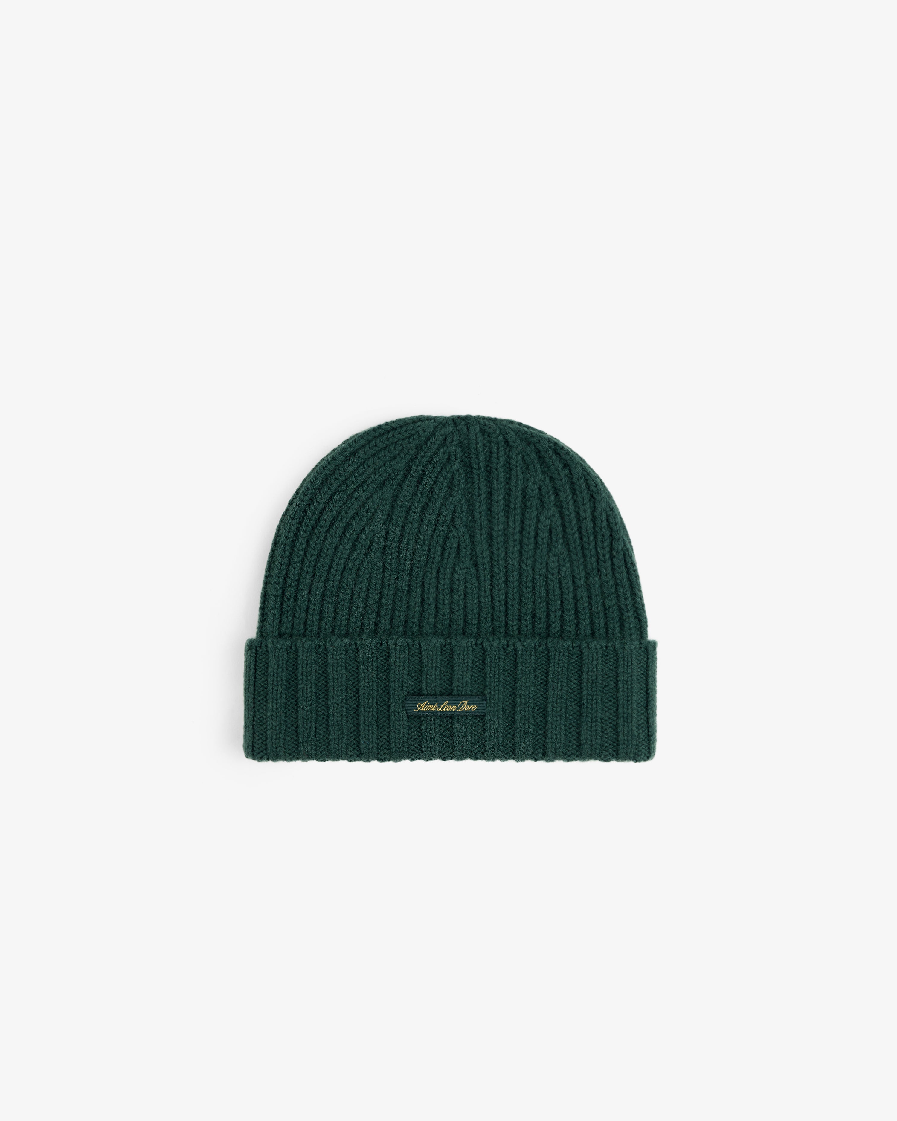 Dark green ribbed knit Cashmere Beanie with a small gold logo tag on the cuff.