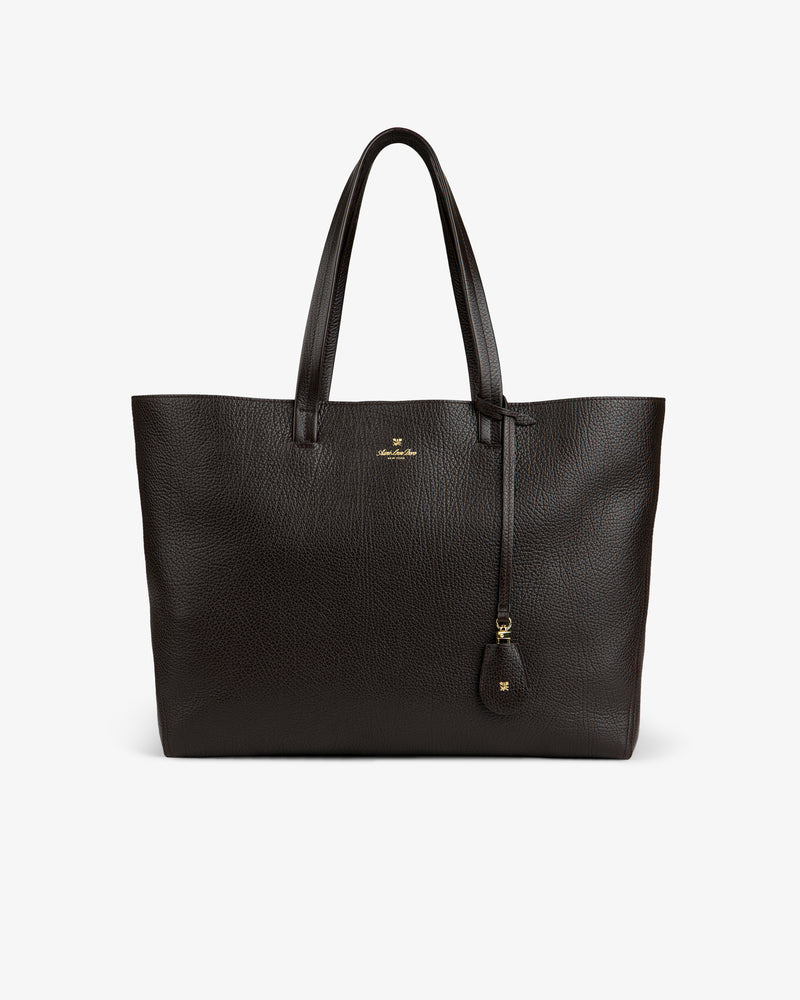 The Tumbled Leather Tote Bag is large, dark brown with two handles and a small gold logo on the front.