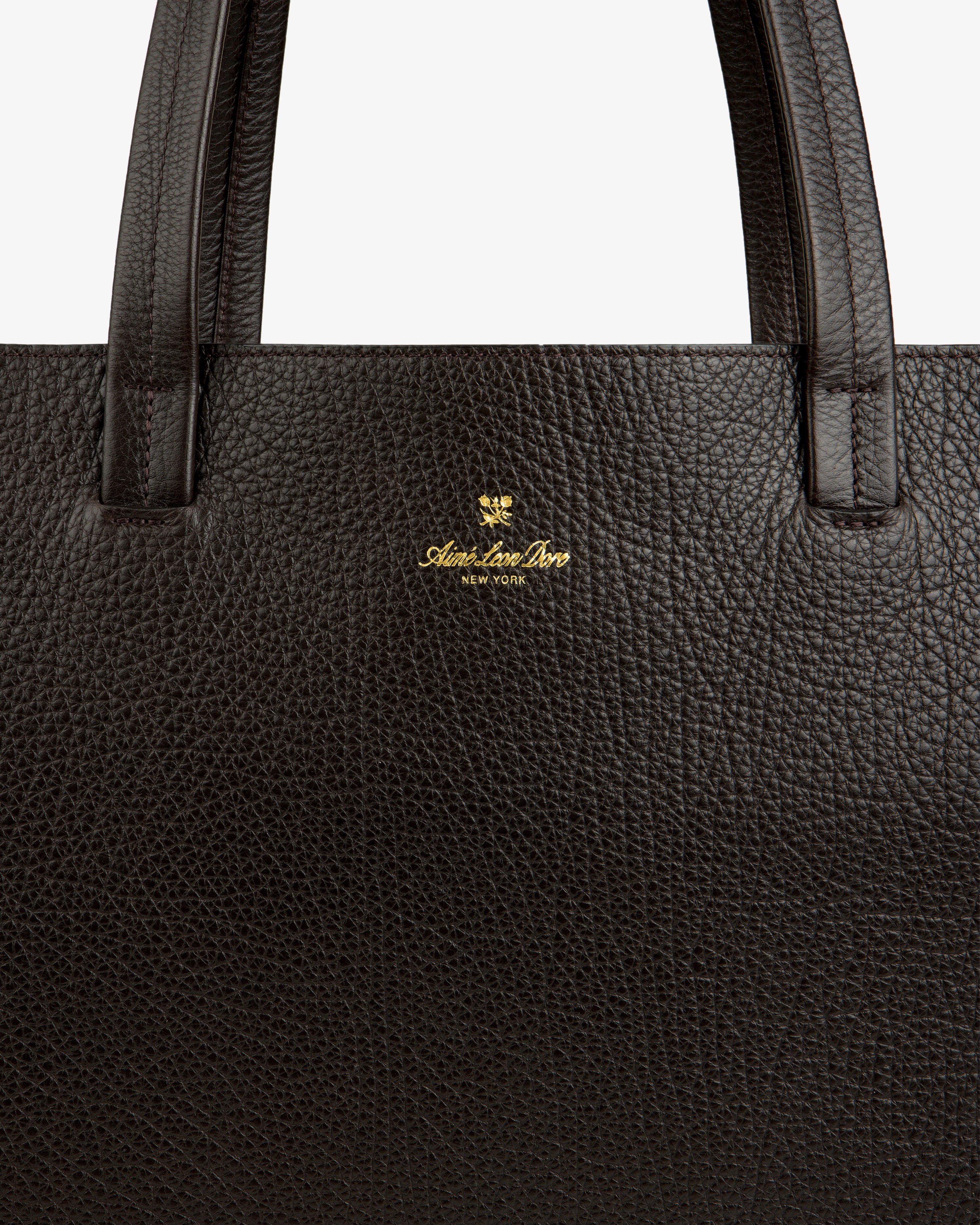 Close-up of a dark brown Tumbled Leather Tote Bag with gold Aspinal of London New York logo near the handle.
