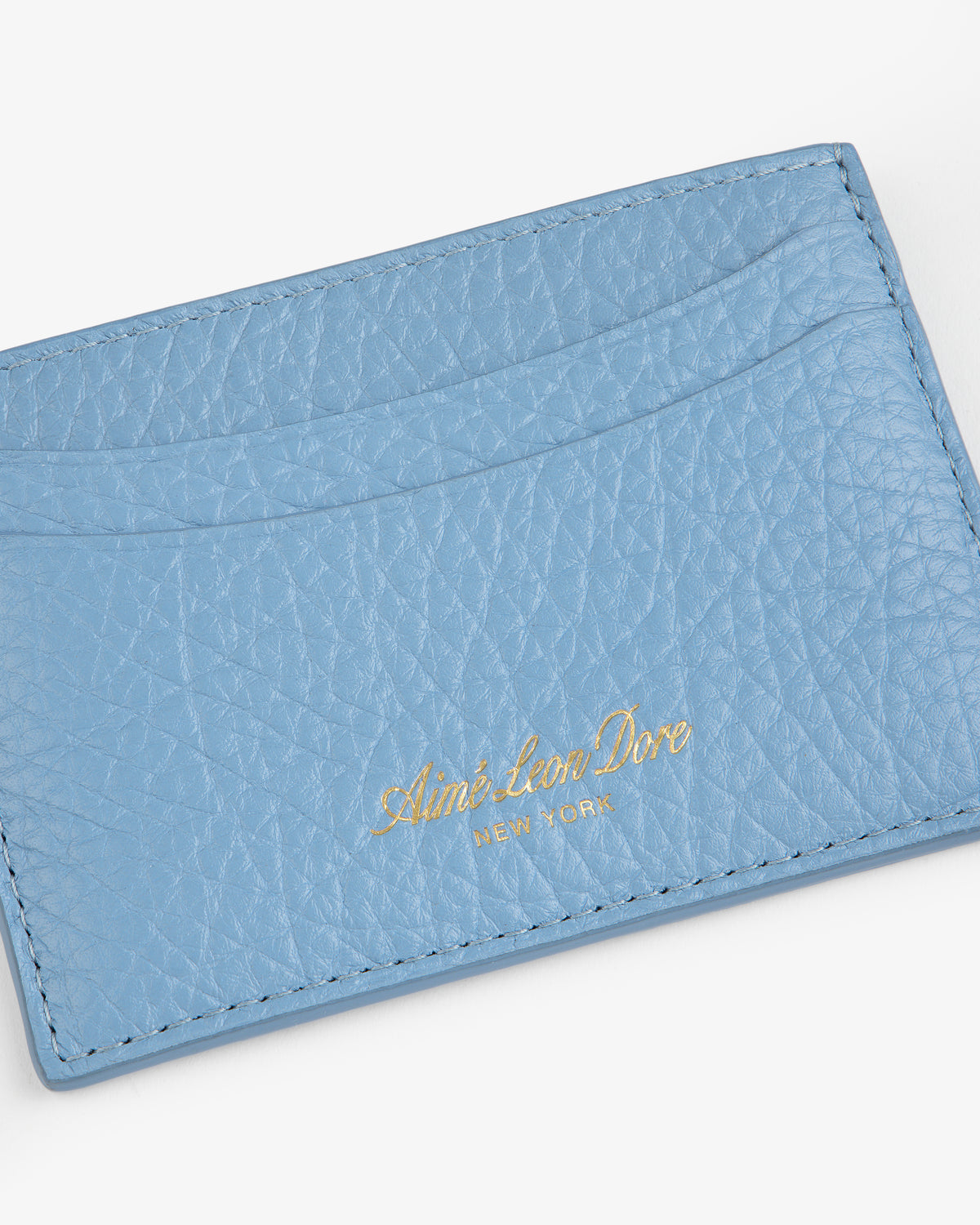 Tumbled Leather Card Holder in light blue leather with gold Aimé Leon Dore New York text, on white background.