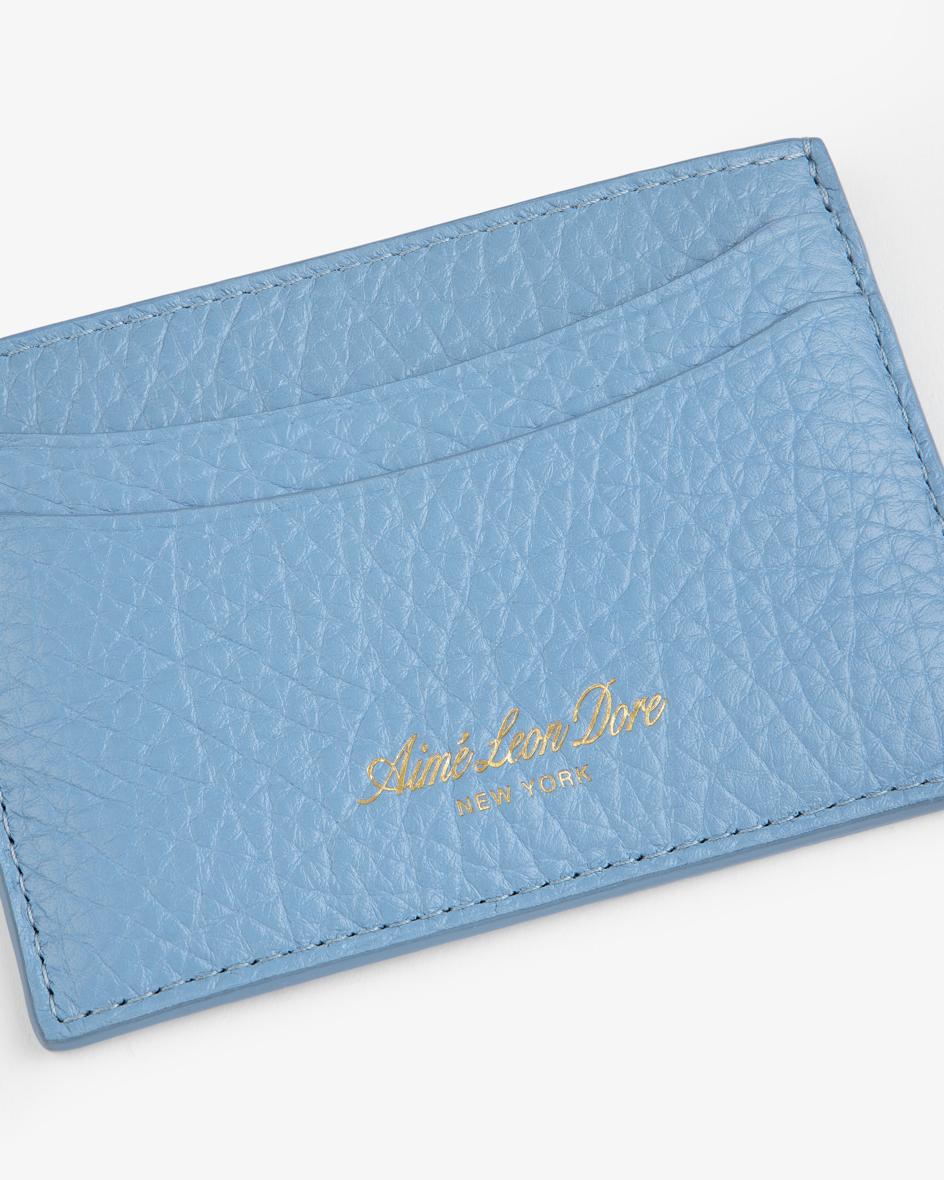 Tumbled Leather Card Holder in light blue leather with gold Aimé Leon Dore New York text, on white background.