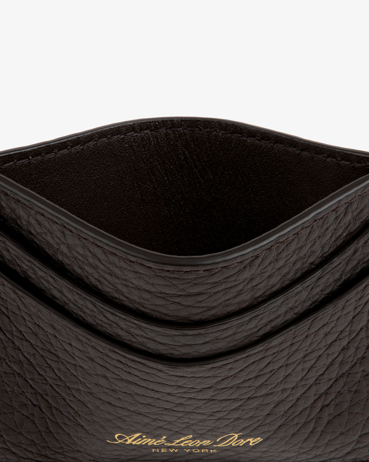 Close-up of a dark Tumbled Leather Card Holder with gold Aimé Leon Dore New York text on the front.