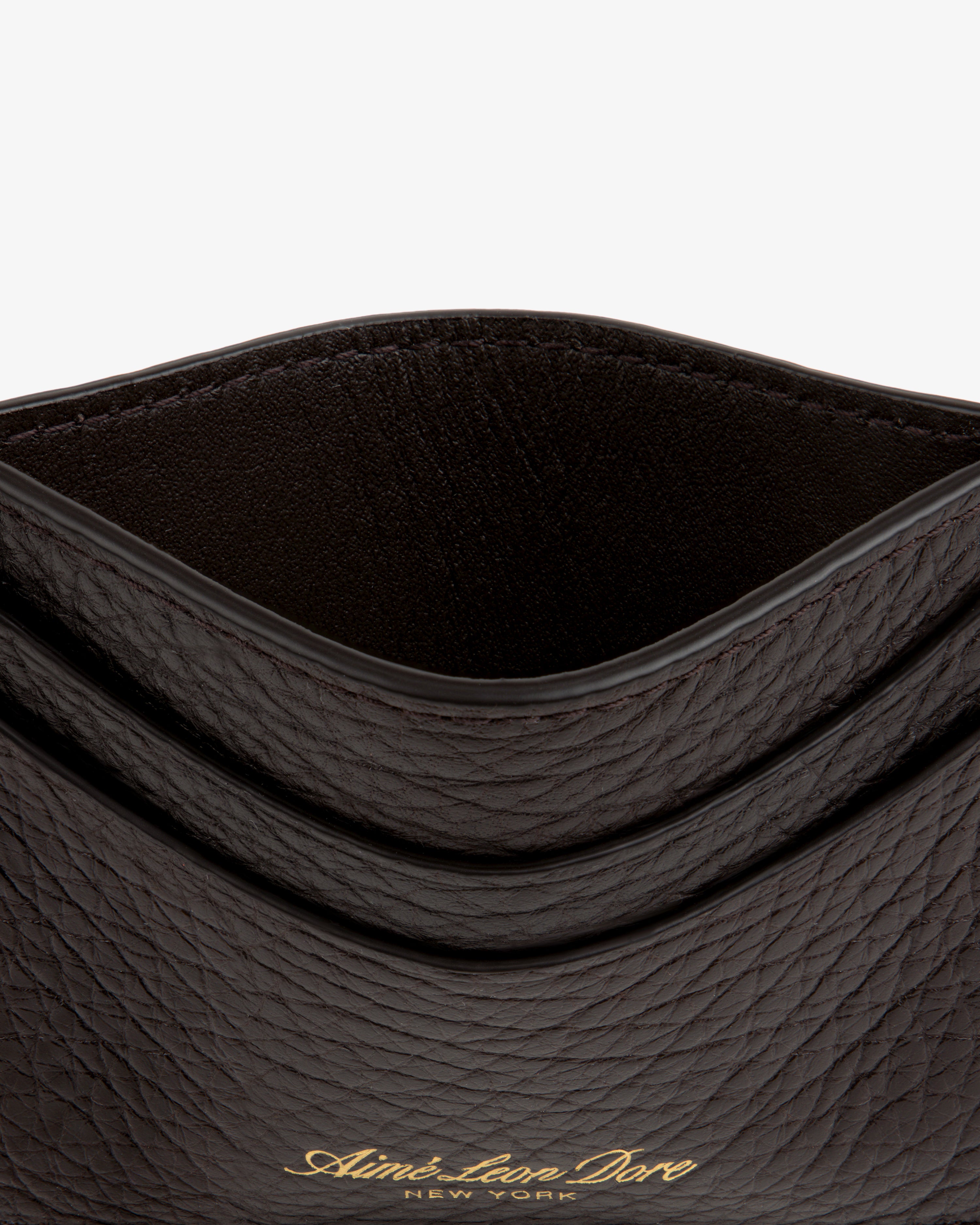 Close-up of a dark Tumbled Leather Card Holder with gold Aimé Leon Dore New York text on the front.