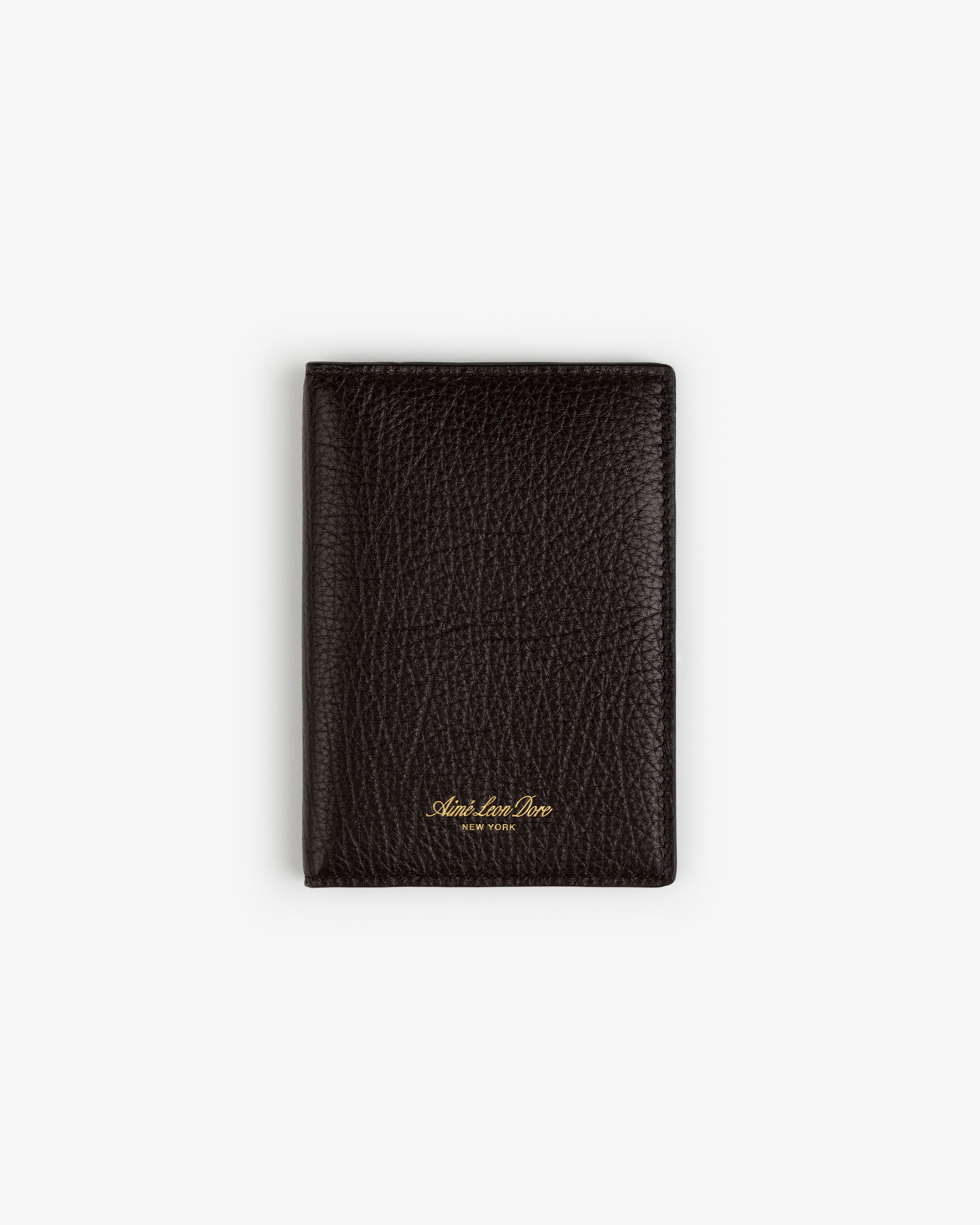 A closed Tumbled Leather Passport Holder in textured dark brown leather with gold text, on a white background.