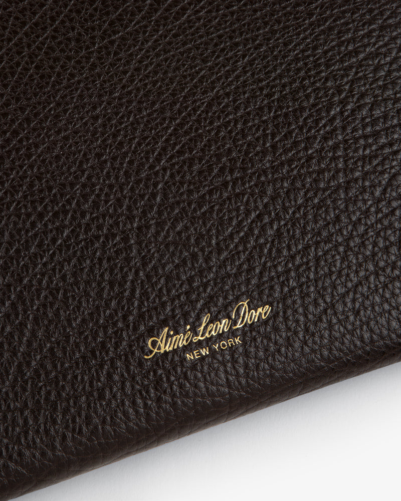 Close-up of black tumbled leather Small Pouch with gold Aimé Leon Dore NEW YORK embossed in the corner.