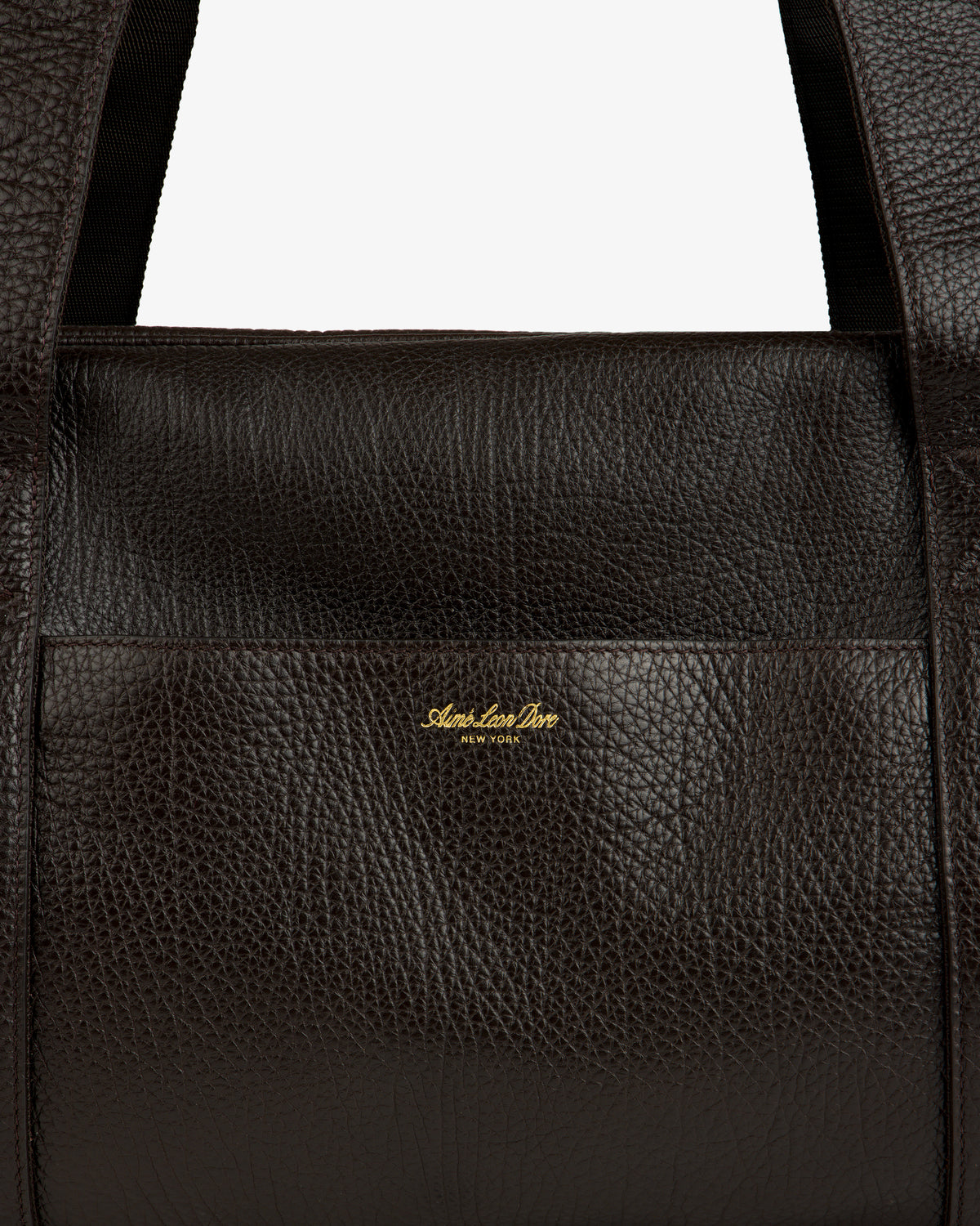 Close-up of Tumbled Leather Duffle in dark brown with visible grain and gold Aimé Leon Dore New York logo on front.