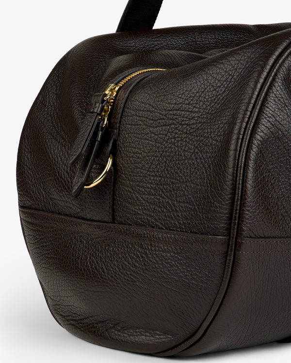 Close-up of the Tumbled Leather Duffle in dark brown with textured leather, gold zipper, and visible stitching.
