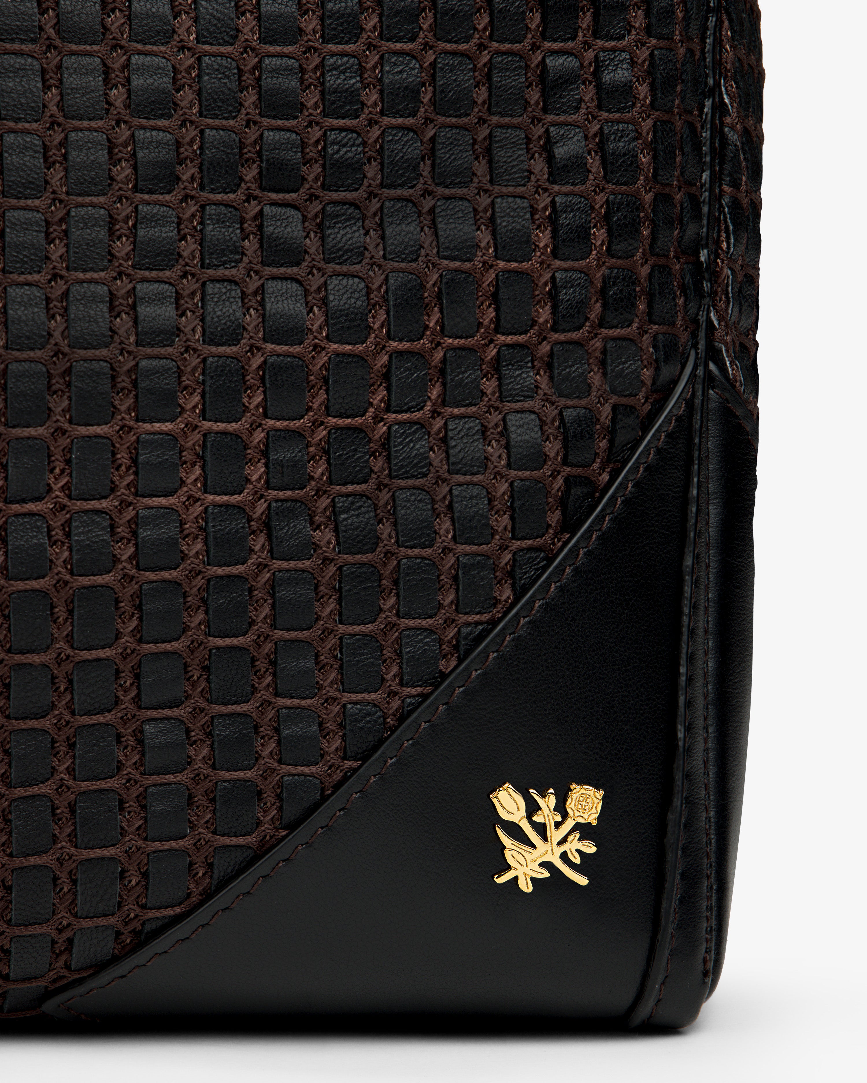 A black and brown Woven Leather Tote Bag with a small gold floral emblem on the corner.