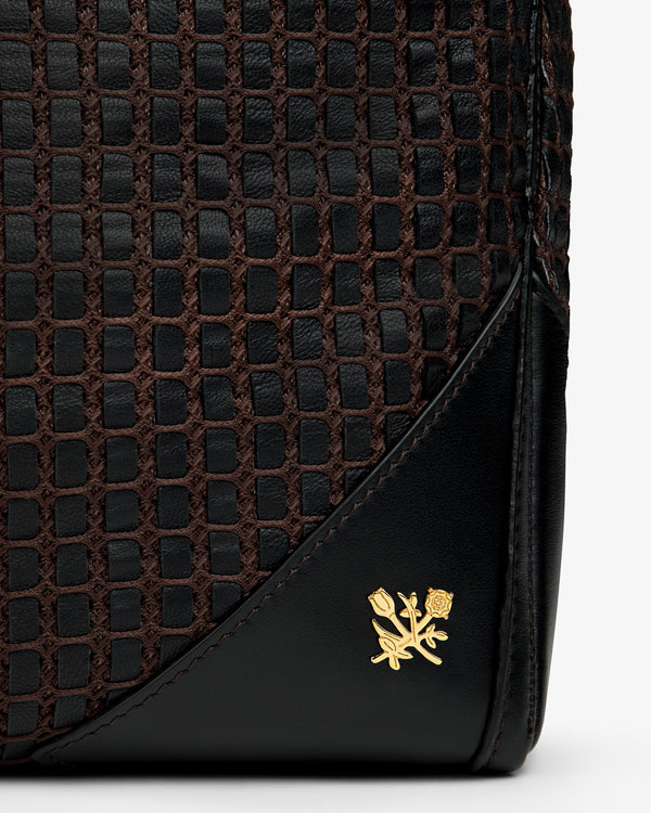 A black and brown Woven Leather Tote Bag with a small gold floral emblem on the corner.