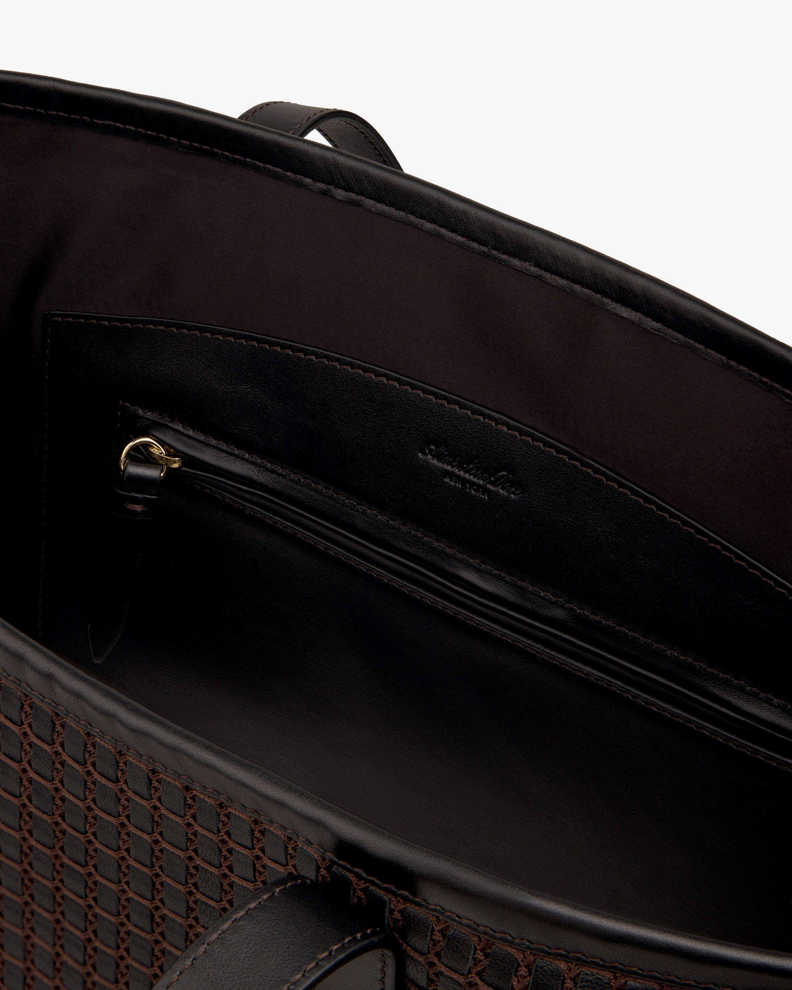 Interior view of a dark Woven Leather Tote Bag showing a zippered pocket.