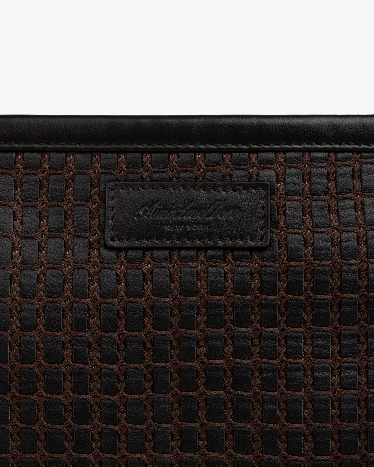 Close-up of a brown Woven Leather Tote Bag featuring a branded leather patch in the center.