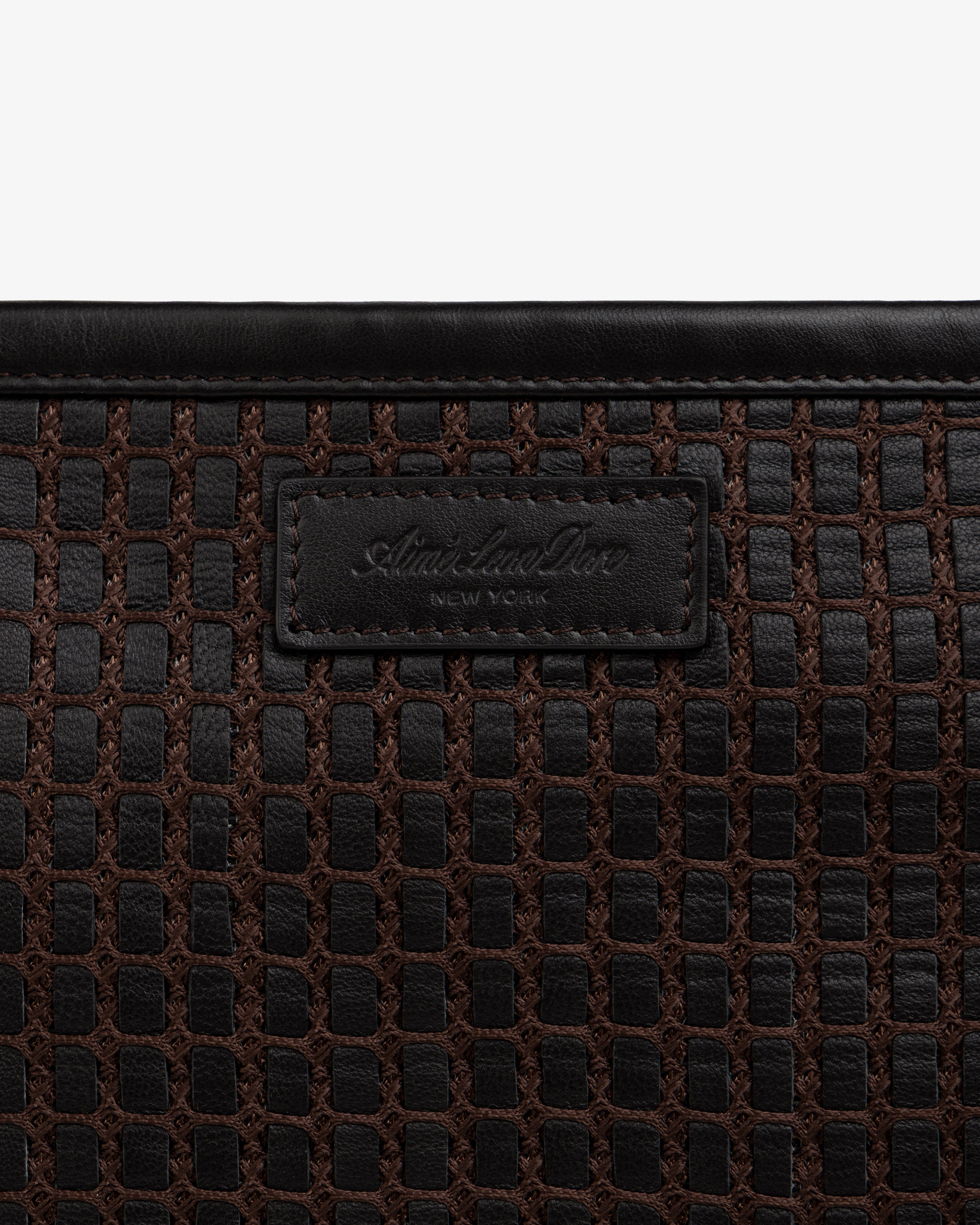 Close-up of a brown Woven Leather Tote Bag featuring a branded leather patch in the center.