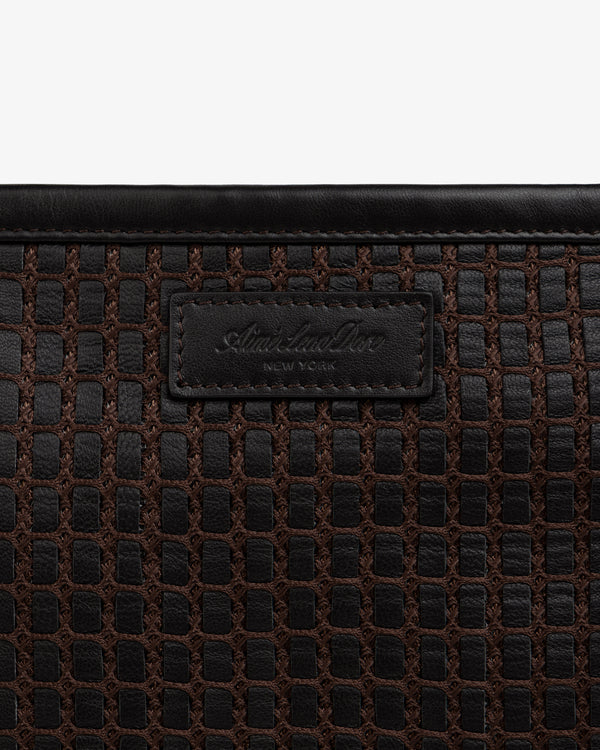 Close-up of a brown Woven Leather Tote Bag featuring a branded leather patch in the center.