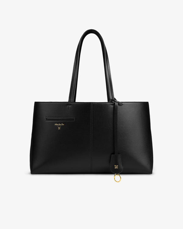 Napa Leather Shoulder Bag in black with double straps and a gold logo charm hanging from the handle.