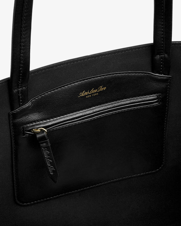 Interior of a black Napa Leather Shoulder Bag with a zippered pocket featuring gold lettering.