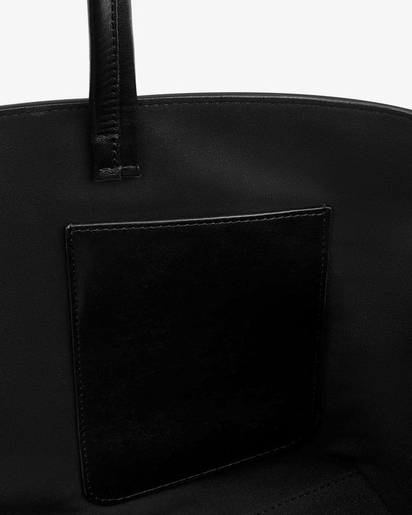 Interior of a black Napa Leather Shoulder Bag showing a flat pocket stitched onto the lining and one attached strap.