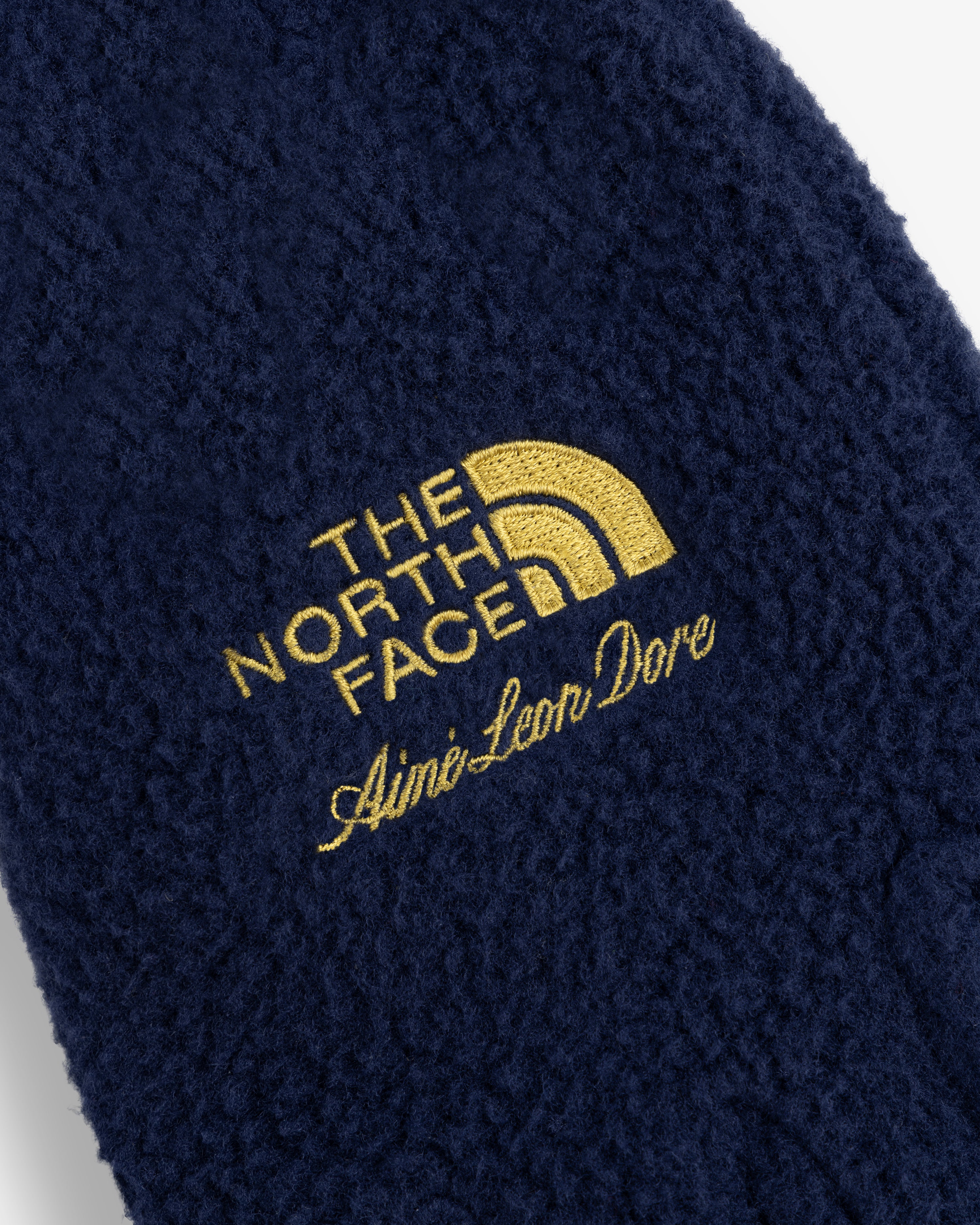 Close-up of ALD / The North Face Fleece Gloves with yellow logos embroidered on navy blue fleece.