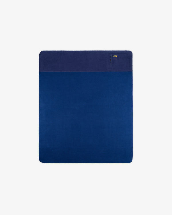 ALD / The North Face Packable Fleece Blanket: square blue throw with dark section, zip pocket; shown on white.