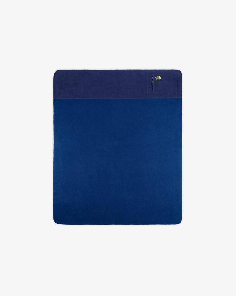 ALD / The North Face Packable Fleece Blanket: square blue throw with dark section, zip pocket; shown on white.