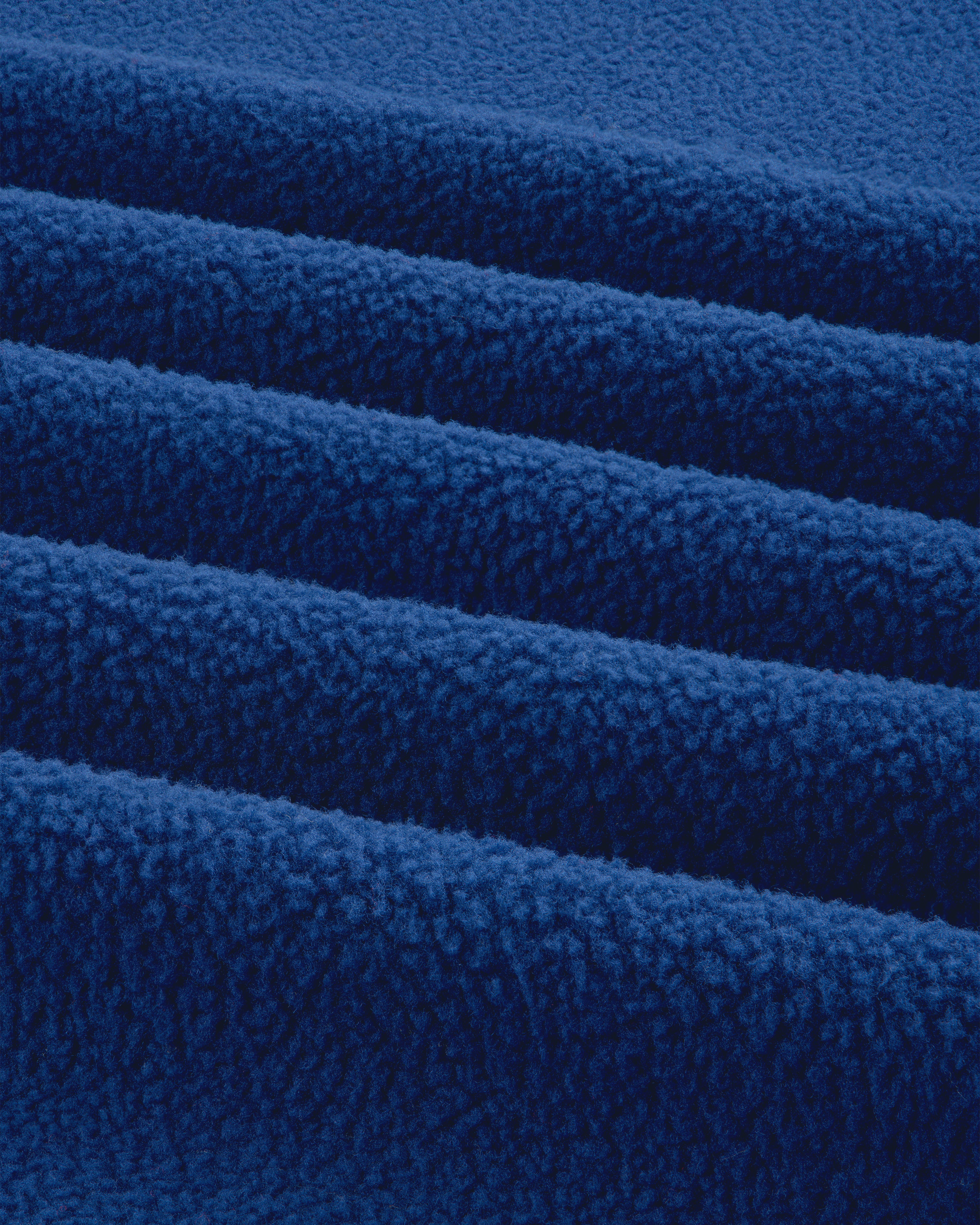 Close-up of ALD / The North Face Denali Fleece Scarf shows soft blue fabric with textured surface and parallel folds.