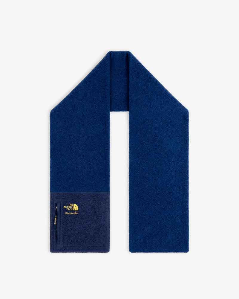 ALD / The North Face Denali fleece scarf in blue with zippered pocket and yellow logo on one end, shown on white.