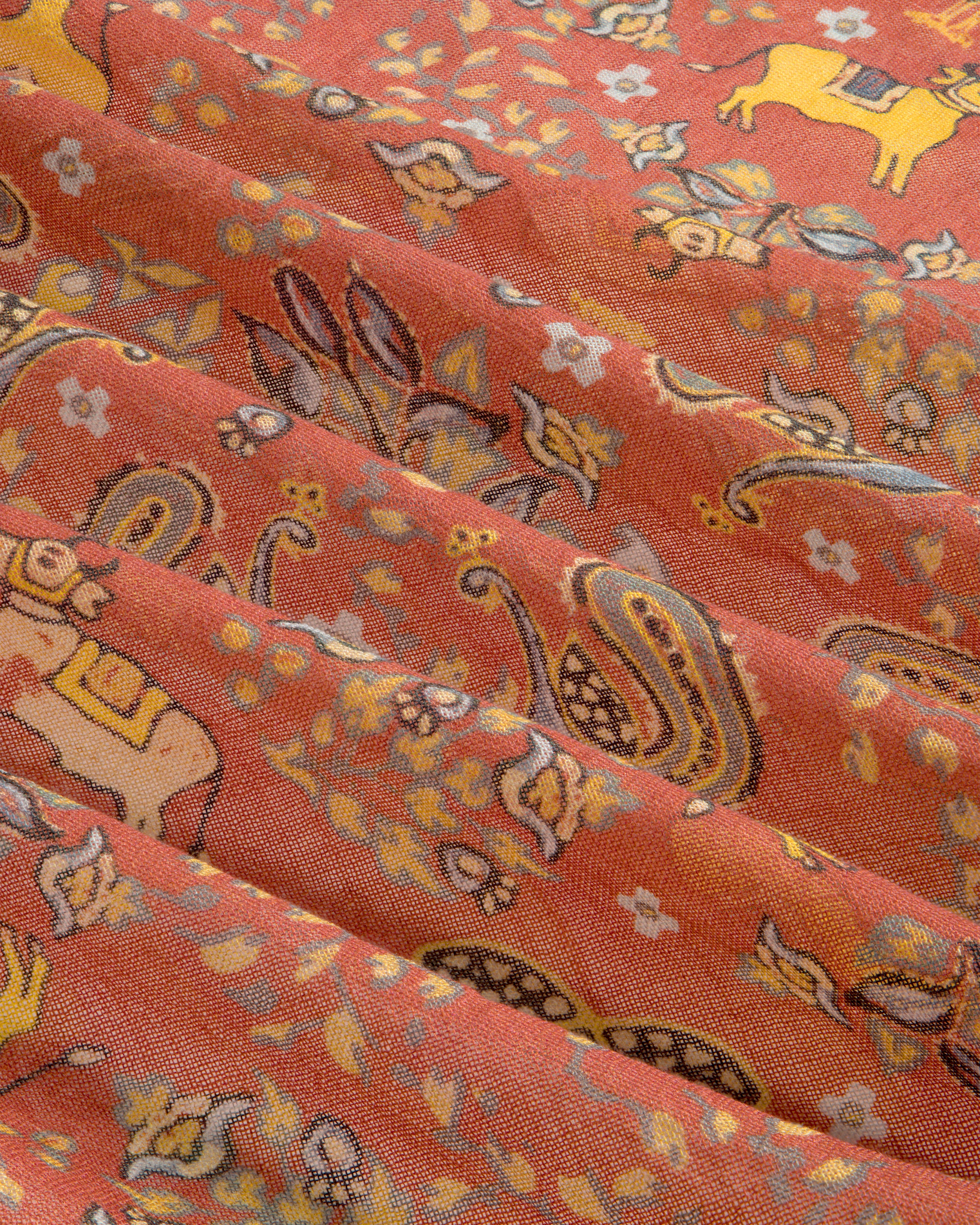 Archival Print Wool Silk Bandana in orange with yellow animal, paisley, folds, and small white floral details.