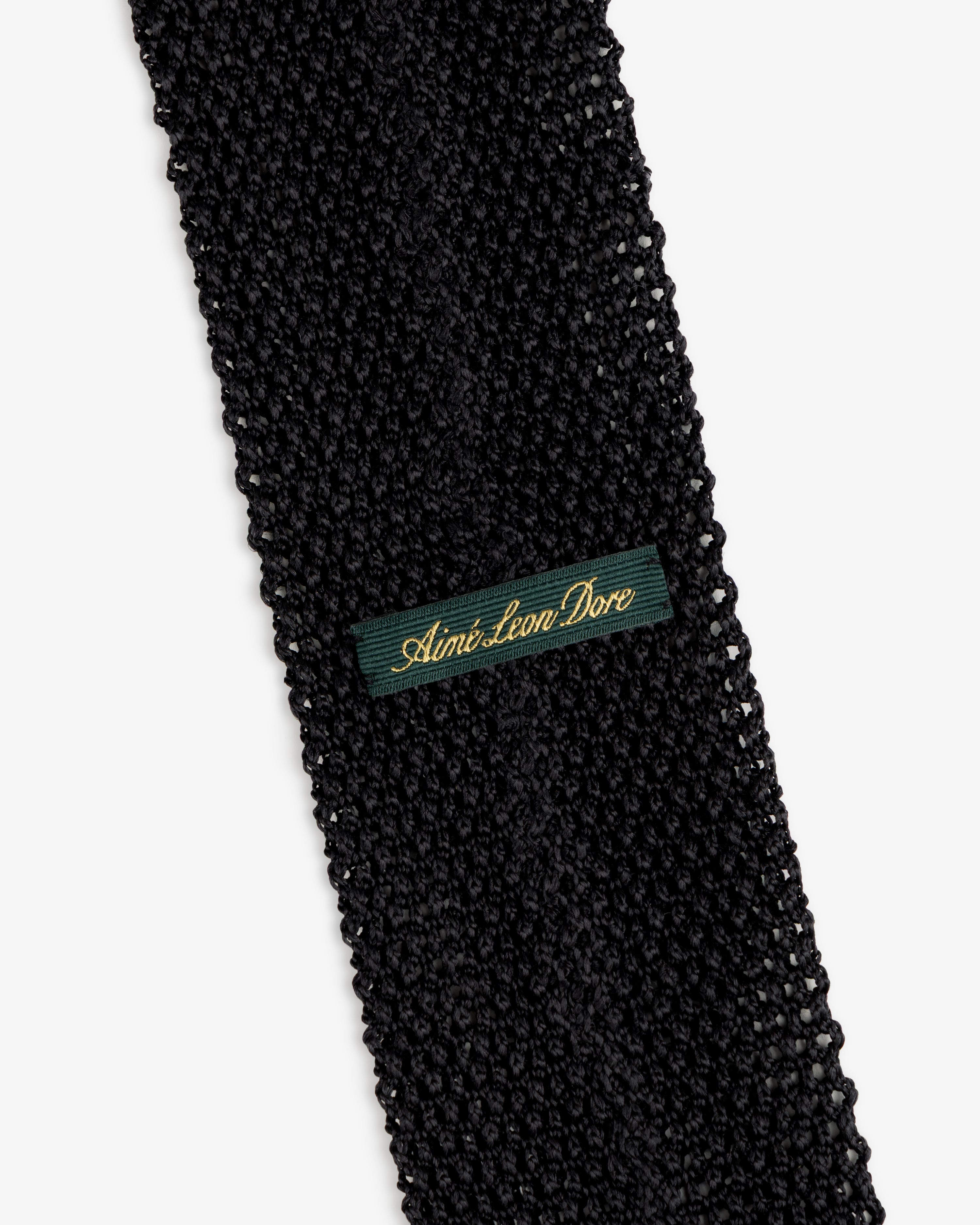 Black Crest Silk Knit Tie with a green rectangular label featuring gold embroidered text.