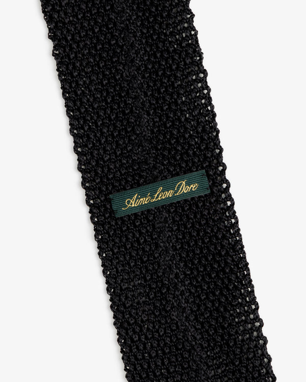 Black Crest Silk Knit Tie with a green rectangular label featuring gold embroidered text.