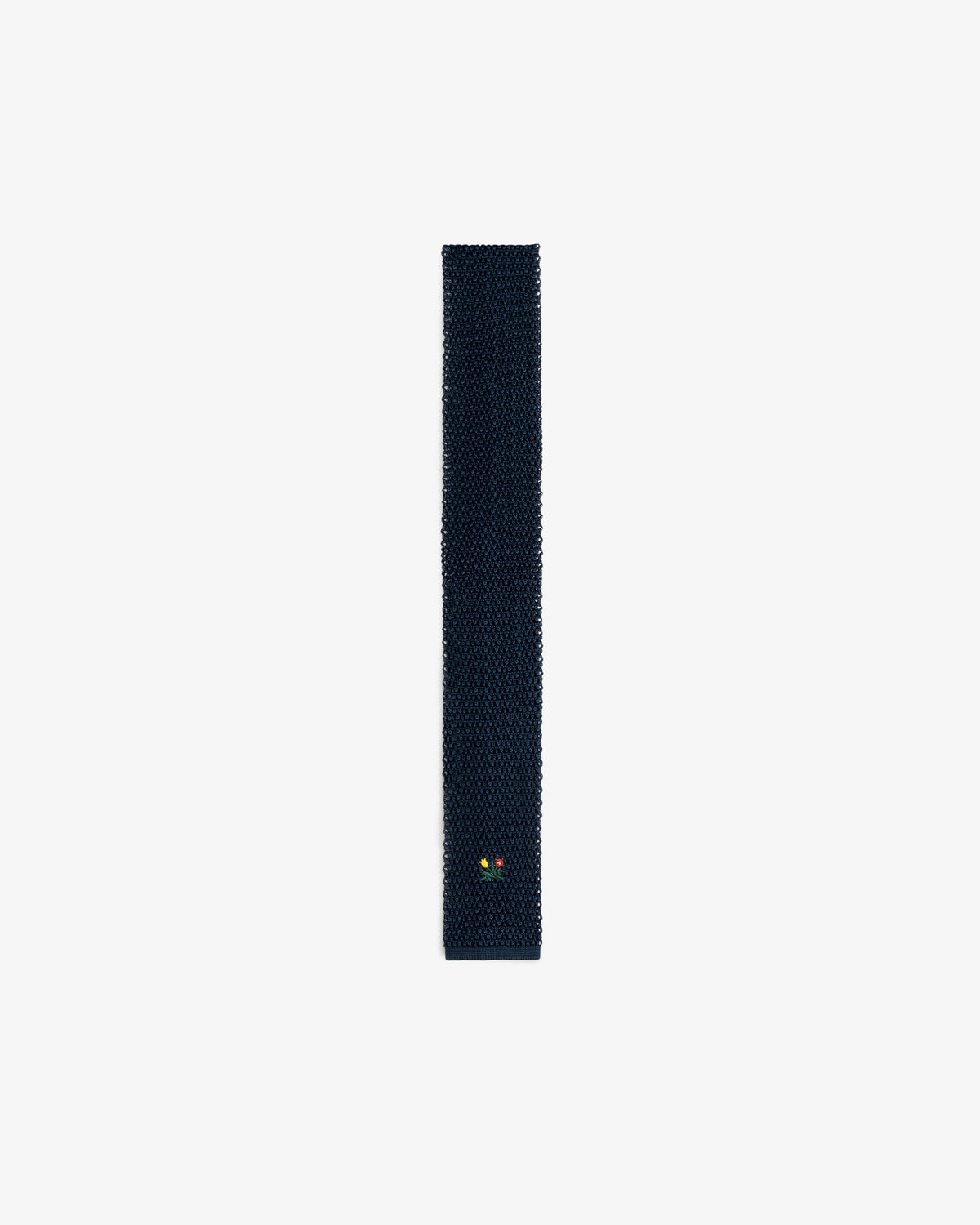 Crest Silk Knit Tie in dark blue with a small yellow and red floral emblem near the bottom.
