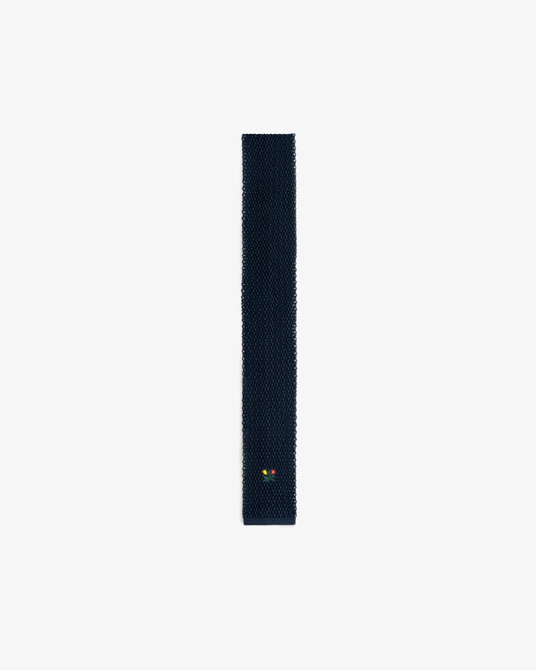 Crest Silk Knit Tie in dark blue with a small yellow and red floral emblem near the bottom.