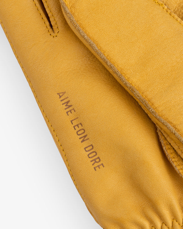 Mustard yellow leather Wakayama Gloves with the brand name stamped on the wrist.