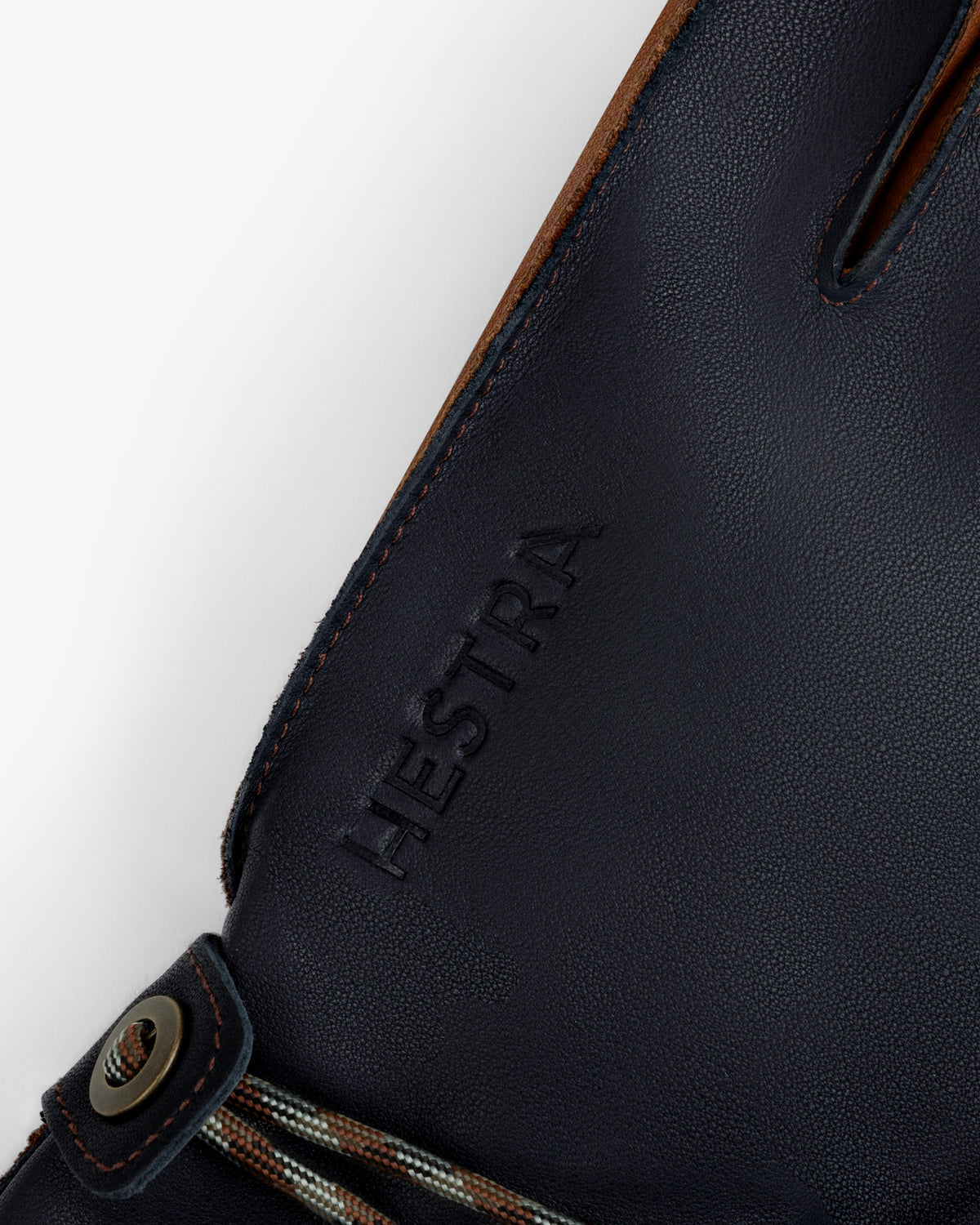 Close-up of navy blue leather Wakayama Gloves featuring an embossed logo and a wrist cord with a metal eyelet.