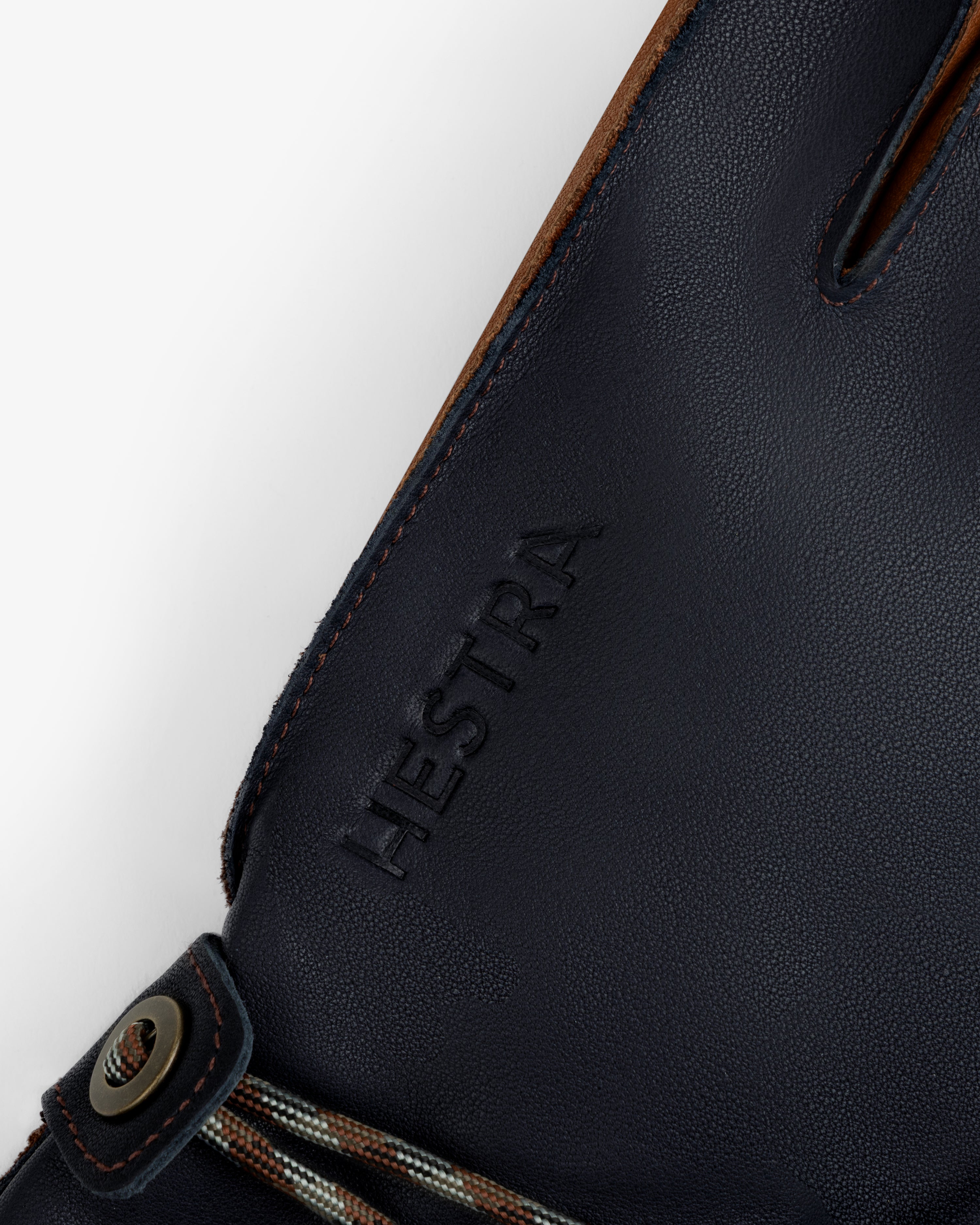 Close-up of navy blue leather Wakayama Gloves featuring an embossed logo and a wrist cord with a metal eyelet.